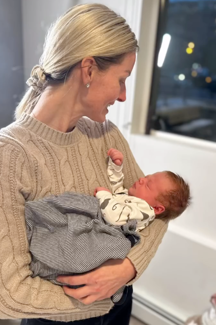 Woman holding a baby in a room with a window in the background